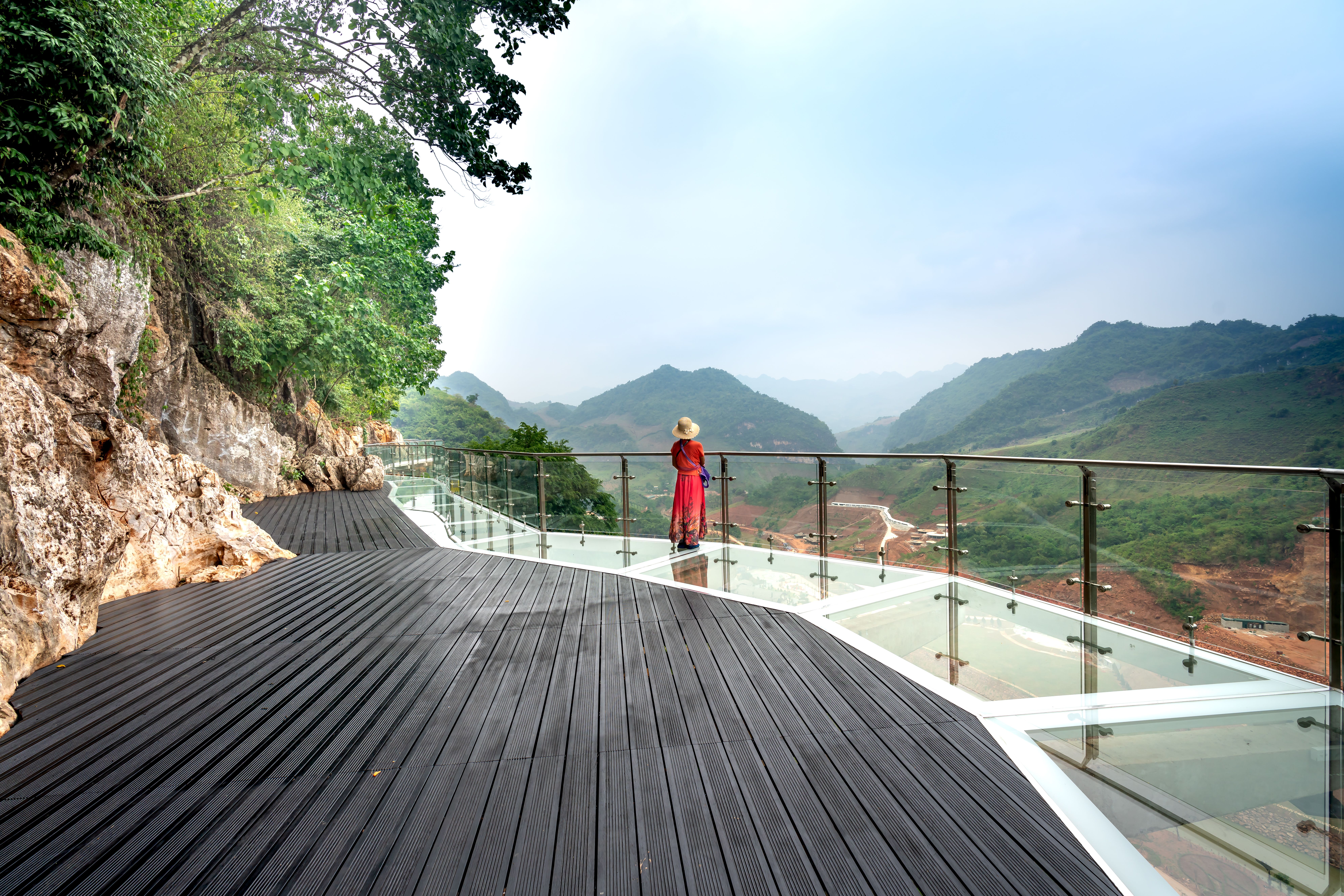 A traveller on a skywalk over misty mountains